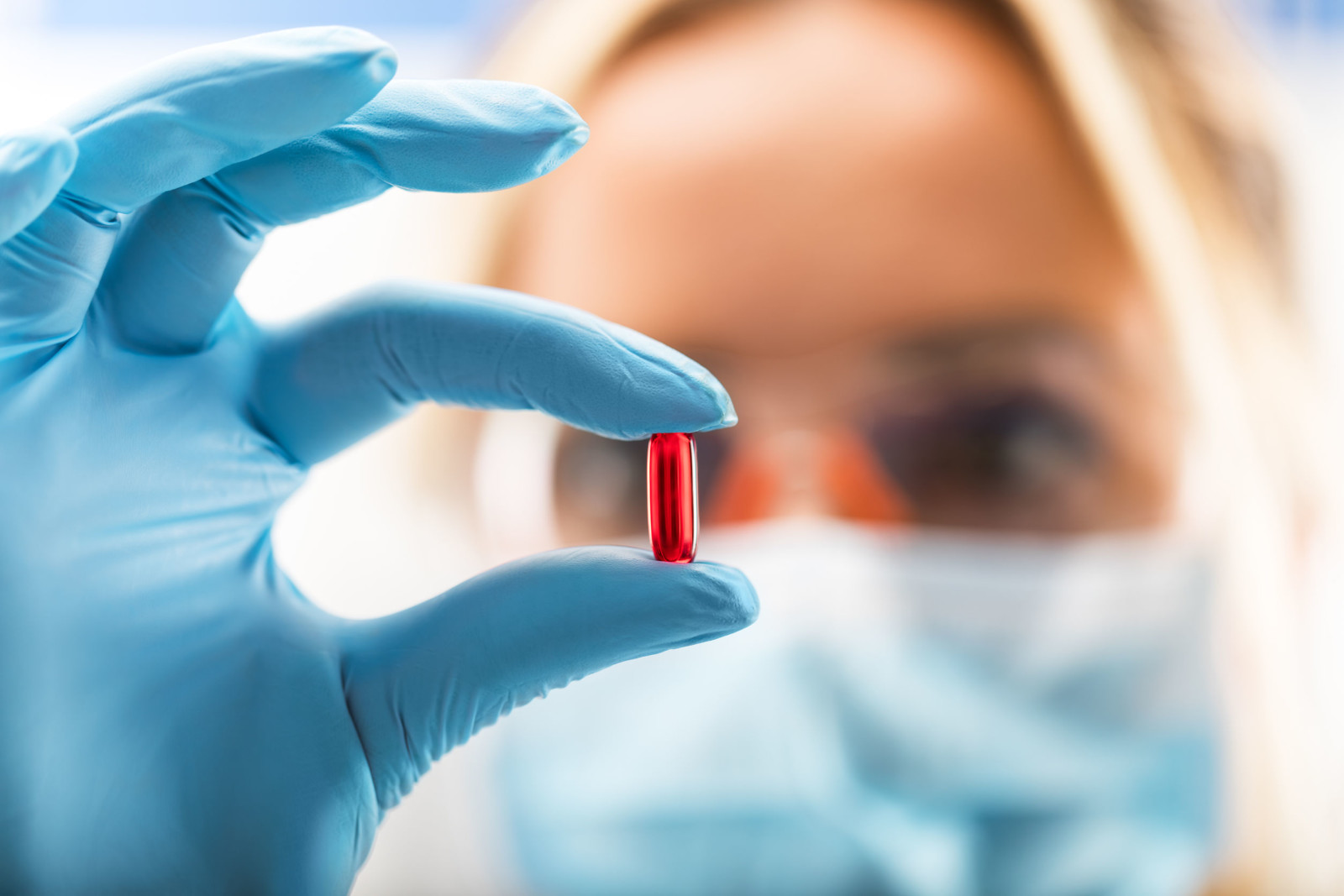 Young attractive female scientist holding a red transparent pill Pharmaceutical Daily News